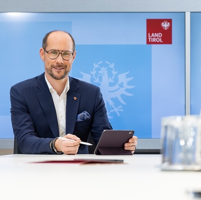 Landesrat Mario Gerber sitzt am Schreibtisch und arbeitet am Computer.